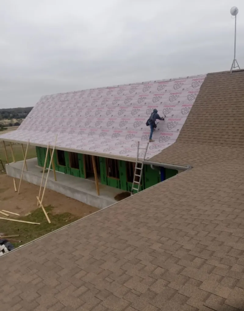 Worker preparing underlayment for a metal roof installation in Cedar Grove